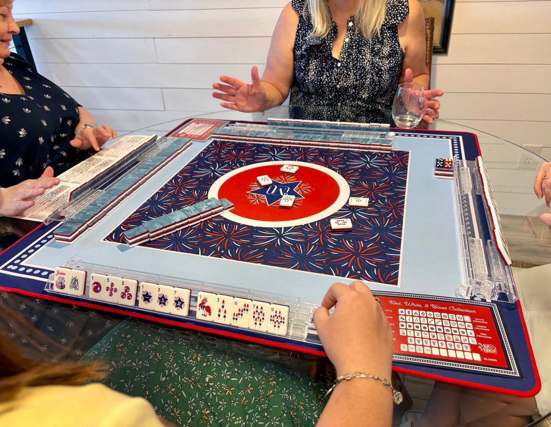 Four women playing mahjong with the Mac + Miller red, white, and blue set