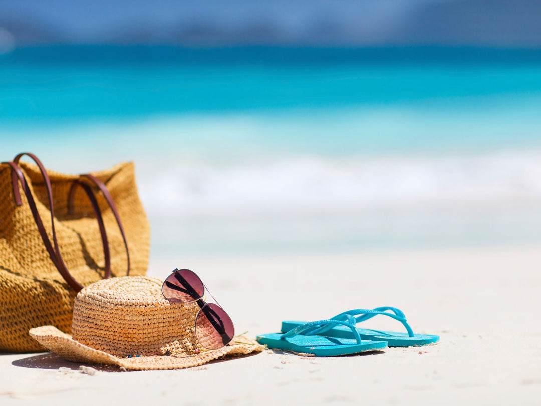 beach bag with hat and flip flops on the beach