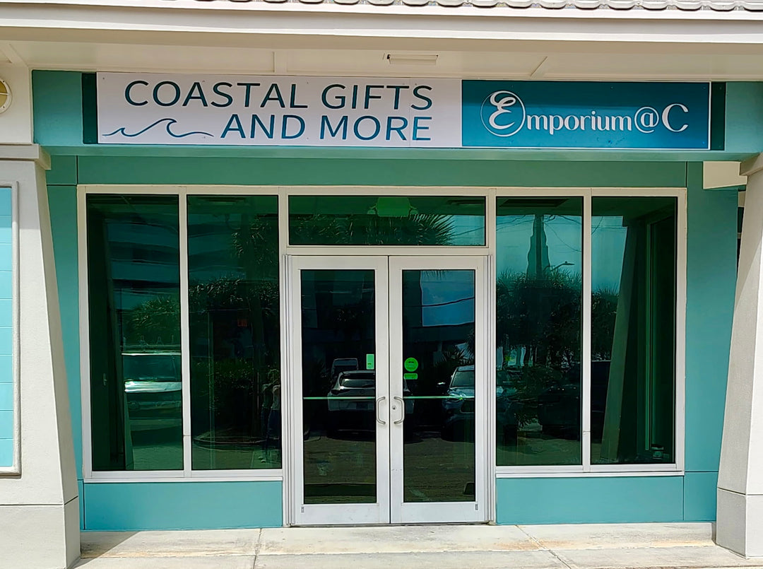 Storefront with 'Coastal Gifts and More Emporium @ C' sign on a teal building.