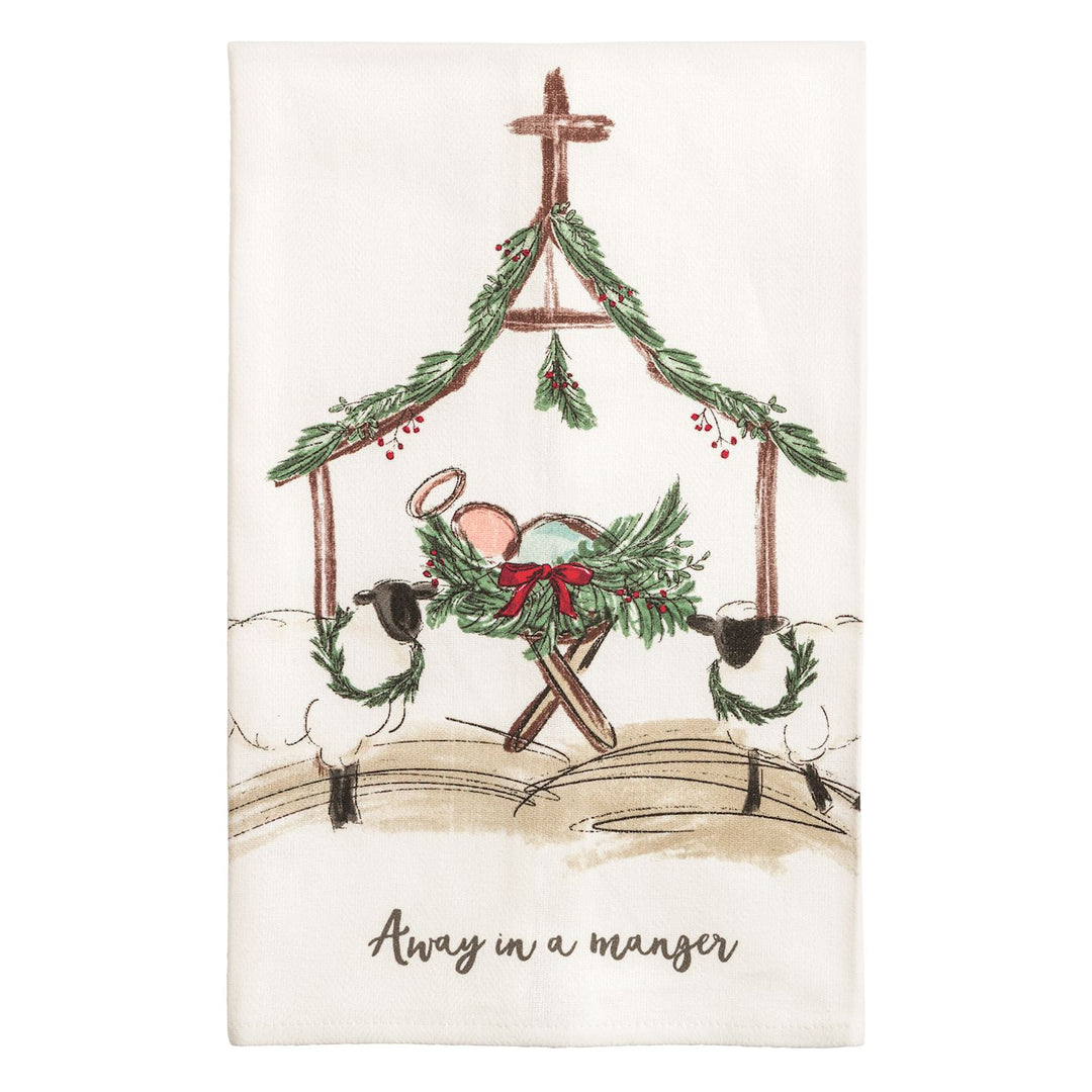 Two cream kitchen towels side by side: the left shows a watercolor nativity stable with a manger, two sheep wearing wreaths, evergreen garland, and the words &