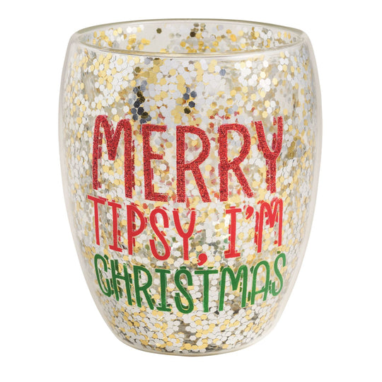 A double-walled stemless wine glass filled with gold and silver confetti glitter, printed with the words "Merry Tipsy, I'm Christmas" in red and green lettering on a white background.
