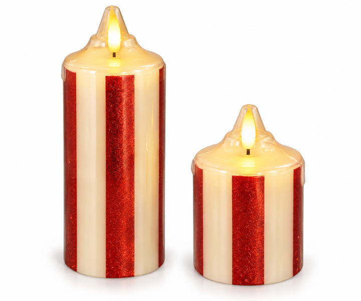 Two cylindrical flameless pillar candles in cream with vertical red glitter stripes and molded dripped-wax tops, each displaying a lit amber LED flame, shown side by side against a white background.