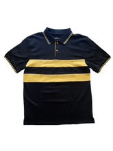 A short-sleeve polo shirt with a navy body, a wide gold chest stripe, a ribbed polo collar with contrast tipping, and a two-button placket, displayed flat against a light background.