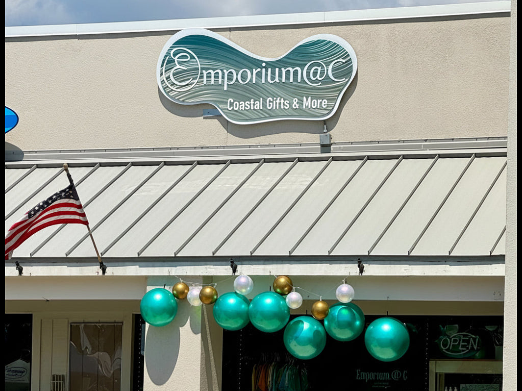 Storefront with 'Emporium @ C' sign and decorative balloons on a sunny day.