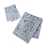 A rectangular tablecloth and a folded napkin in a blue and white botanical block-print pattern, shown flat against a white background.