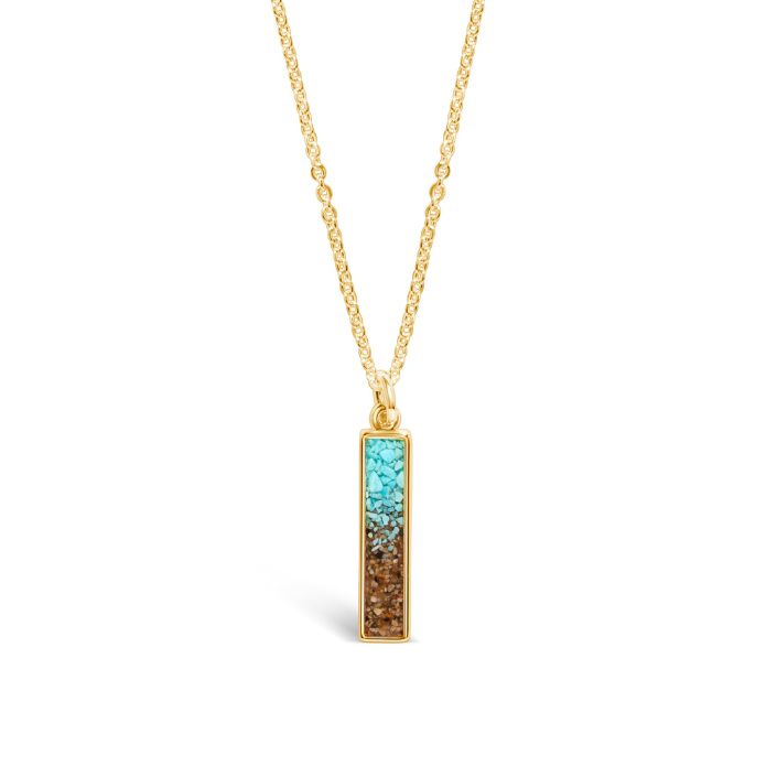 A gold-tone vertical bar pendant necklace with a gradient fill of crushed turquoise stones at the top blending into natural brown sand at the bottom, suspended on a delicate gold-tone link chain against a white background.