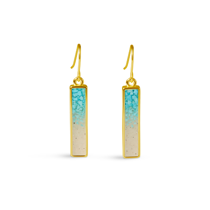 A pair of vertical rectangular bar drop earrings with a gold-tone bezel frame, filled with crushed turquoise stones that fade into a sand-toned base, hanging from gold-tone French hook wires.