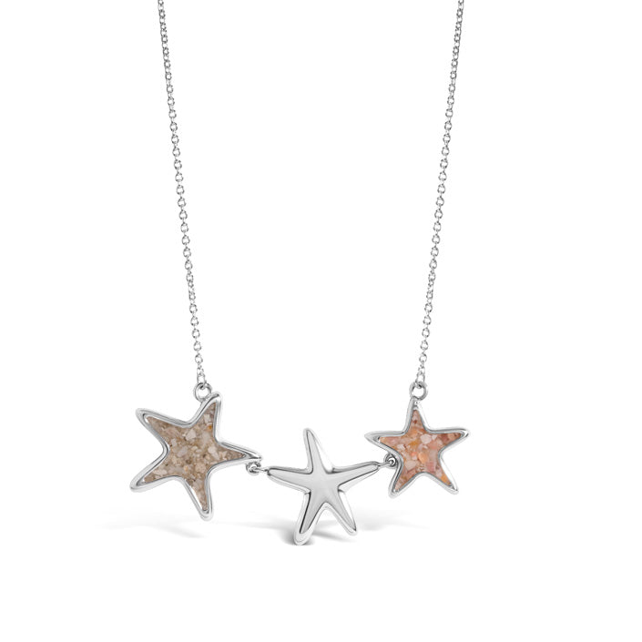 Three starfish pendants on a delicate silver-tone rolo chain, with two open-frame starfish filled with natural sand flanking a smaller solid polished starfish at the center.